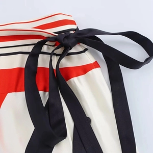 Detail of red, white and black striped skirt featuring a black satin waist tie