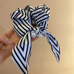 Detail of striped satin scrunchie featuring a bow with white pearls and sparkling rhinestones