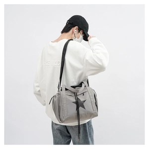 Detailed view of gray nylon crossbody bag with black star motif and adjustable strap