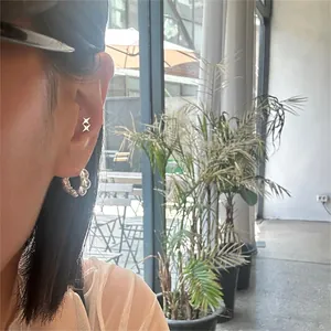 Close-up of 925 sterling silver star stud and lava texture hoop earring on ear