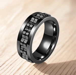 Close-up of black titanium steel anti-anxiety ring with rotating gear texture