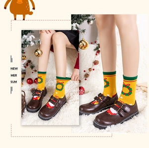 Detail of yellow Christmas mid-calf cotton socks with Santa Claus and festive wreath pattern