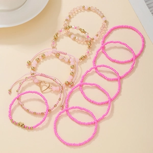 Detailed set of pink beaded bracelets with heart charms and golden metallic accents