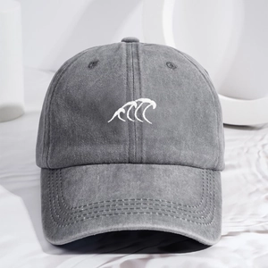 Washed dark gray baseball cap with white wave embroidery on a minimalist stand