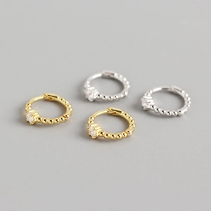 Detailed view of four small hoop earrings in gold and silver with CZ stone and beaded edges