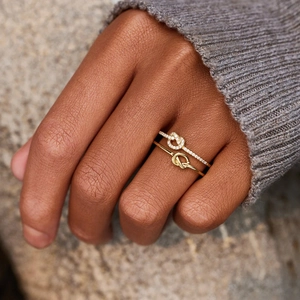Macro shot of gold knot rings set with zircon accents on a natural stone background