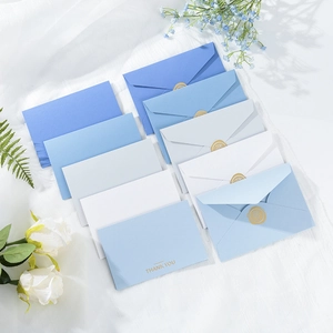 Blue and white envelopes with gold wax seal and Thank You card on white fabric background