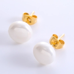 Detailed close-up of golden pearl stud earrings with polished finish on a white background