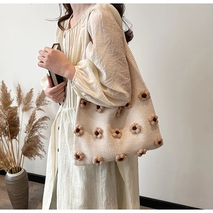 Detail view of a cream knit tote bag with 3D floral accents on a shoulder strap