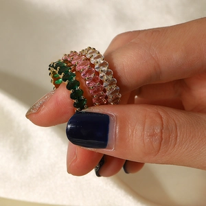 Detail of three stackable gold rings featuring green, purple and white oval cut zircons