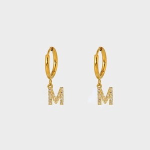 Detail of gold plated stainless steel hoop earring featuring a zircon pavé letter M charm