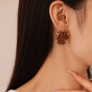 Detail of vintage woven leather and gold metal hoop earring worn by a model