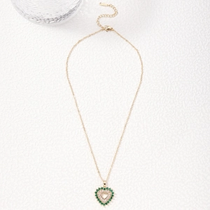 Golden heart necklace featuring vibrant green and white crystals on a stone surface