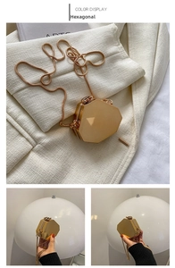 Detail of a geometric gold metal evening bag with mirror finish and snake chain strap