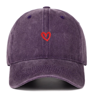 Dettaglio del ricamo a cuore rosso sul tessuto denim lavato del berretto viola