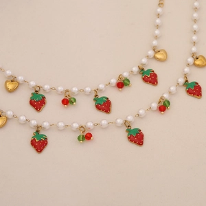 Detail of strawberry and cherry charms with heart on white pearl necklace strand