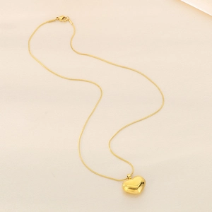 Close-up of a minimalist gold heart pendant on a delicate snake chain necklace