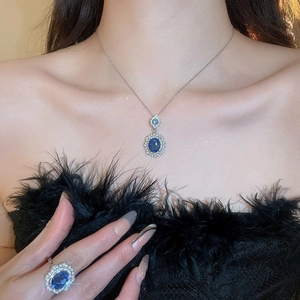 Detailed view of the diamond-set oval blue gemstone necklace and ring set on model