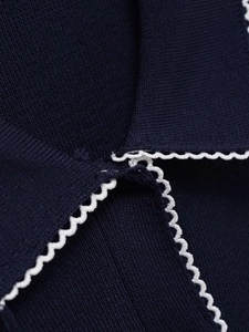 Close-up of dark blue knit shirt collar featuring delicate white scalloped edge detailing