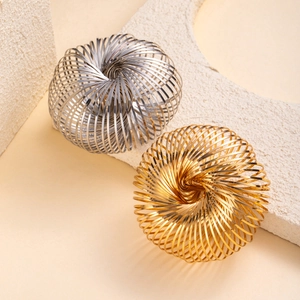 Modern gold and silver kinetic flow ring bracelets on a textured stone display