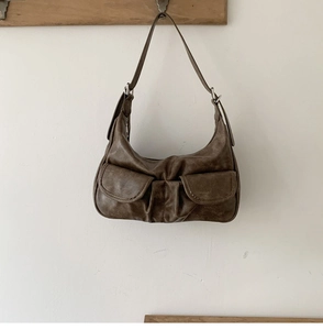 Detailed view of a brown vintage leather bag featuring pleated design and two magnetic pockets