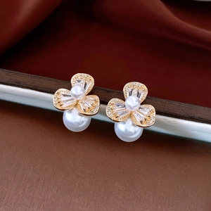 Macro detail of gold flower pearl earrings with crystals on brown satin background
