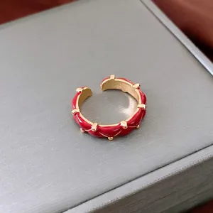 Retro 24K gold plated open ring with red enamel glaze on textured grey jewelry box