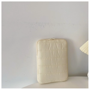 Close-up of beige quilted laptop sleeve with soft stitch texture and zipper closure
