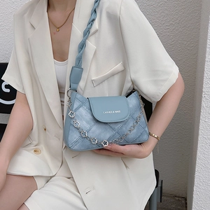 Blue denim patchwork underarm bag with woven strap and flower chain on model