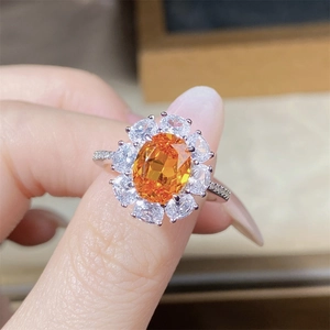 Macro shot of silver ring with large oval orange gemstone and halo flower cluster