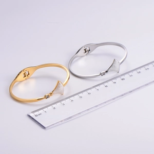 Close-up of gold and silver fan-shaped bangle with white shell inlay and zircon detail