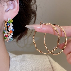 Detail of colorful crystal beads and pearls entwined with gold-plated textured hoop earrings