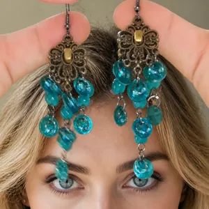Close-up of vintage bronze dangling earrings with blue beads and hollow metal design
