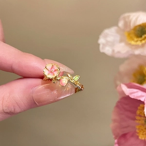 Close-up of 18k gold plated flower ring with pink enamel petals and green leaves