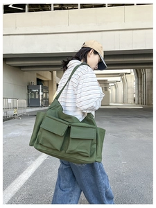 Detailed view of the army green canvas messenger bag featuring large utility pockets