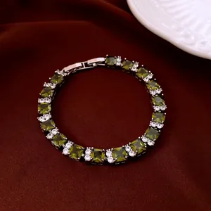 Elegant silver tennis bracelet with square green zircons and white crystals on red silk