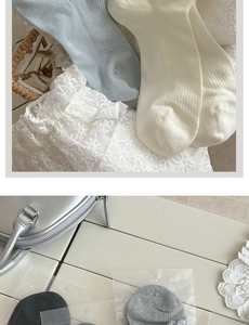 Detail of ribbed knit socks with delicate white lace edges in soft blue and cream colors