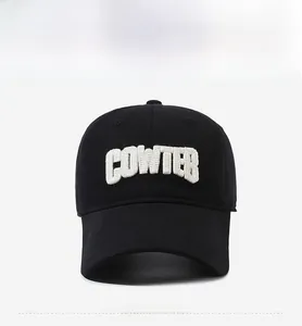 Front detail of black cotton baseball cap featuring 3D white COWTER letter embroidery