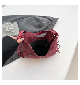 Detail view of burgundy fringe bag featuring interior zipper pocket and metal rivets