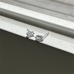Macro shot of silver square-cut zircon stud earrings with sparkling natural light reflection