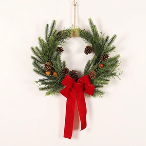 Christmas wreath with green pine needles, pine cones, red berries and a red velvet bow