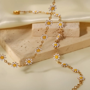 Detalle de cadena de oro 18K con margaritas de esmalte blanco y amarillo en seda