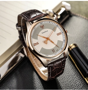 Business style rose gold watch with brown crocodile leather strap on a desk with a pen