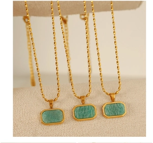 Macro shot of rectangular green amazonite pendant with golden bezel on a beaded chain