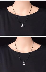 Close-up of minimalist silver pendants with letter J and C encrusted with clear rhinestones