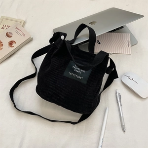 Vue détaillée du mini sac cabas en velours noir avec ordinateur et papeterie