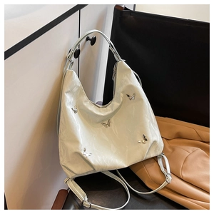 Detail shot of silver butterfly metal buckles on textured cream white leather tote bag