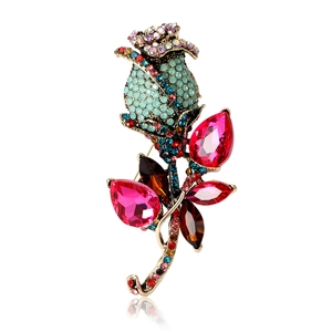 Vintage rose flower brooch with colorful rhinestones on a polished golden metal base