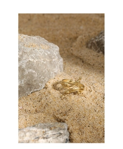 Macro detail of gold S925 sterling silver ring with irregular lava texture on sand