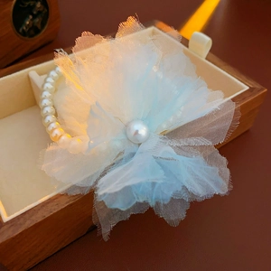Macro shot of light blue mesh flower pearl bracelet resting in a wooden jewelry box